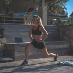 woman in black sports bra and black shorts sitting on concrete bench during daytime